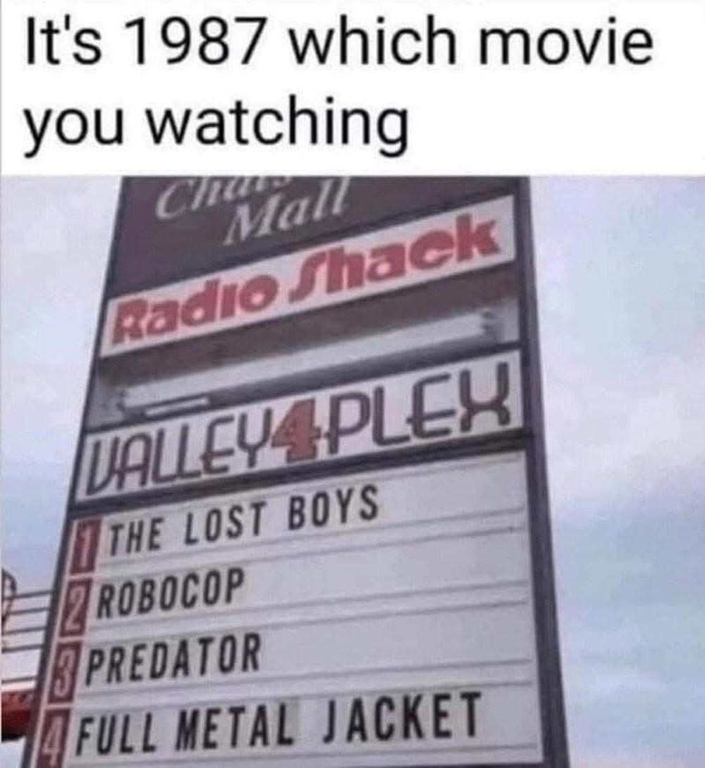 A mall movie theater sign from 1987 lists films: The Lost Boys, Robocop, Predator, and Full Metal Jacket. Above, text asks, Its 1987 which movie you watching?.